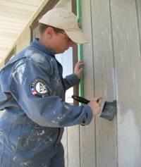 Article Thumbnail. Team Member Aimee Daniels, painting a building at the very same fairgrounds.