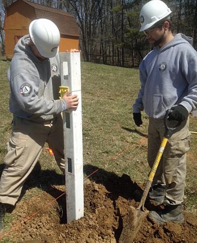 Article Thumbnail.  Nick and Corey position a fence post for the horse’s riding ring.